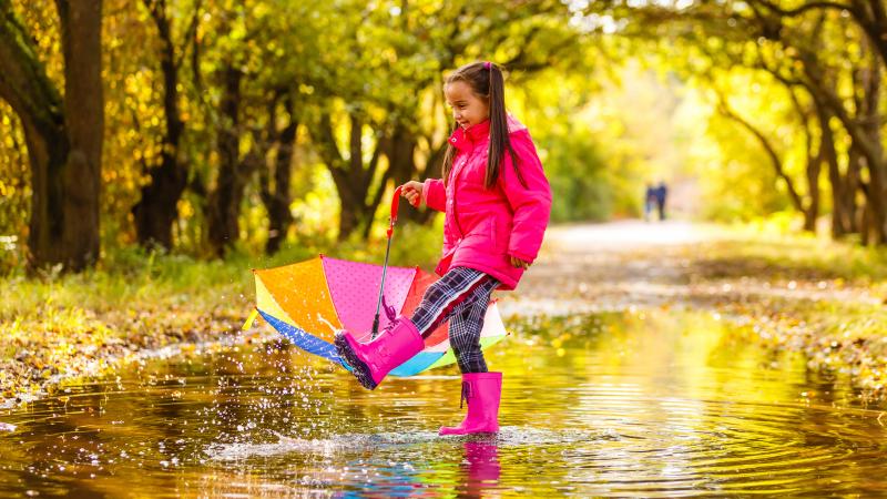 Girl playing in rain puddle